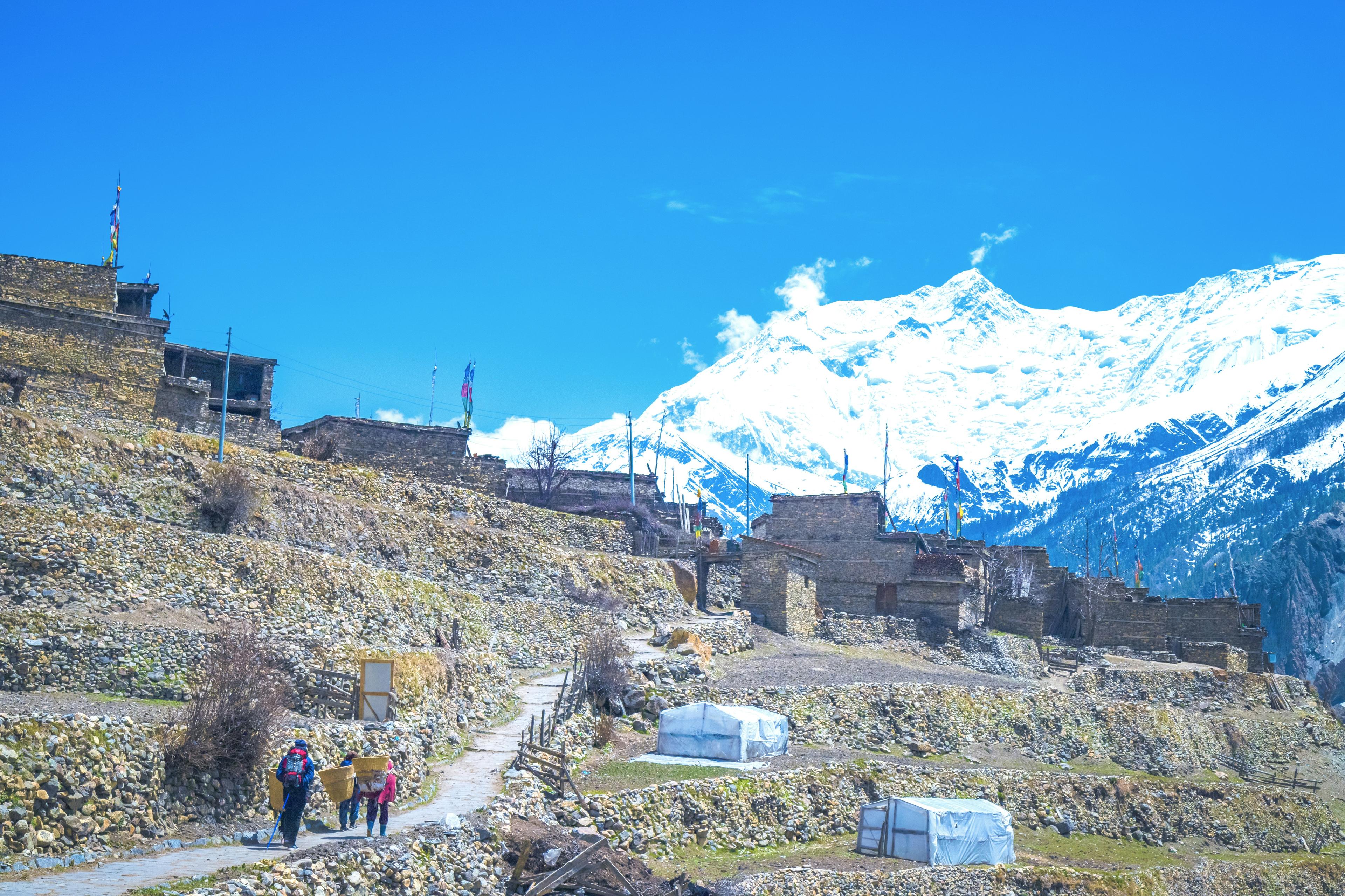 Traditional mountain village in Nepal with snow-capped peaks in the background